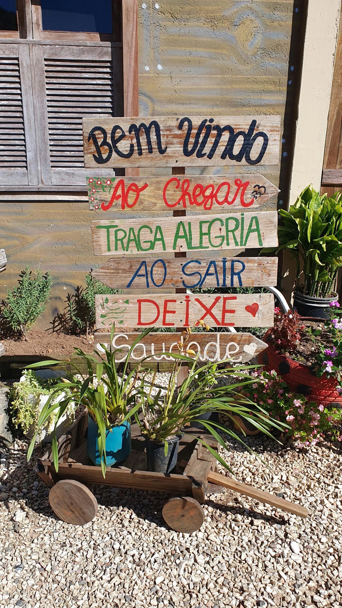 Charming outdoor welcome sign with plants, promoting joy and nostalgia.