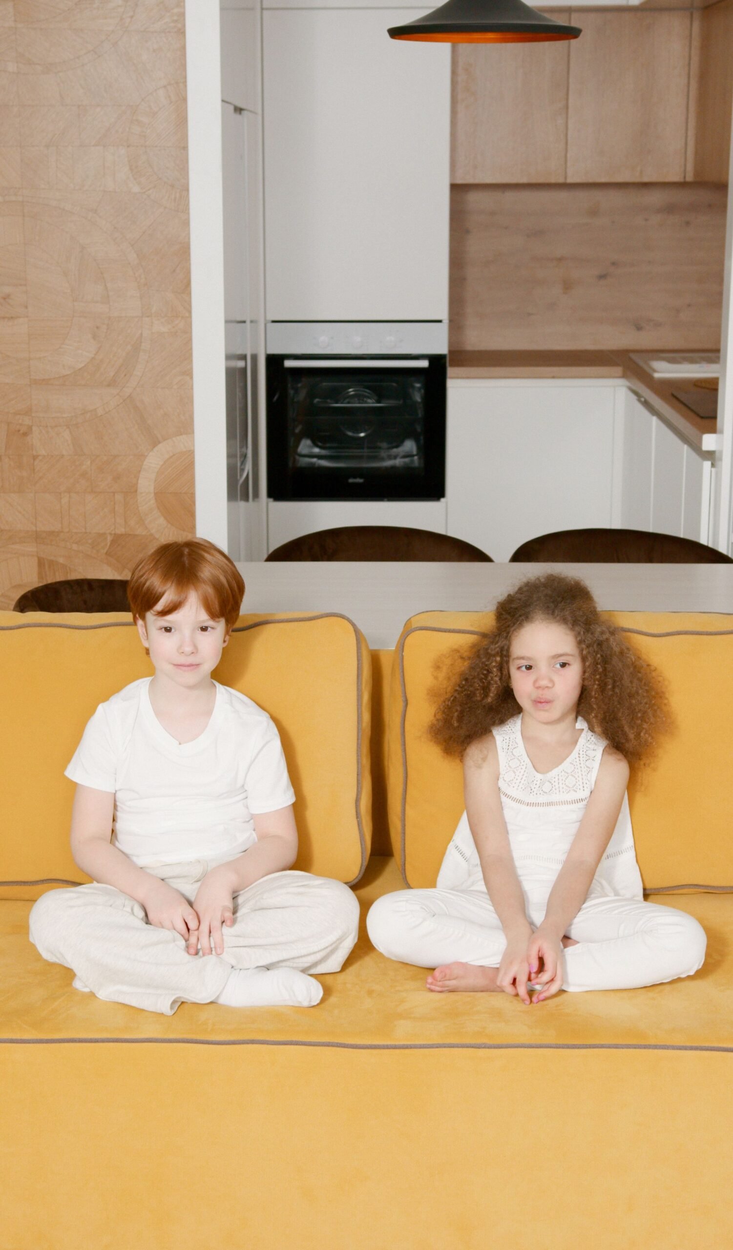 Two children sitting comfortably on a vibrant yellow sofa, offering a cozy and aesthetic ambiance.